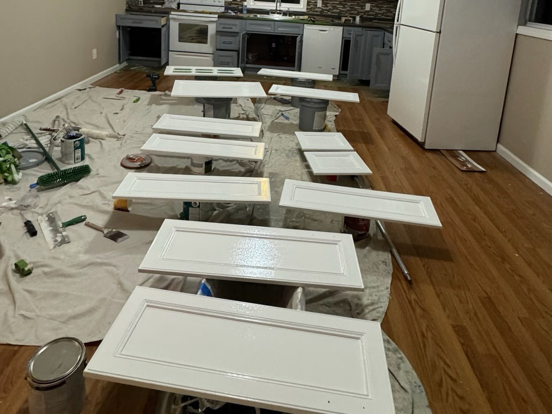 Cabinet doors sprayed white and drying on racks on the job site