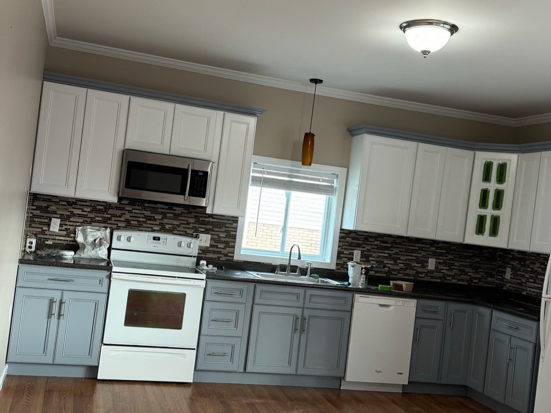 Freshly painted two-tone kitchen with white upper cabinets, grey lower cabinets and dark granite counters
