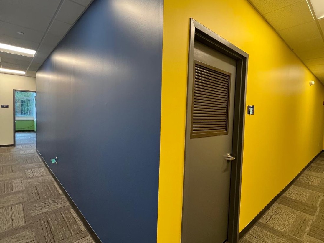 Commercial hallway repainted with a navy accent wall meeting a bright yellow wall in a clean straight line