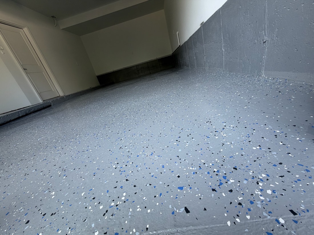Garage floor finished with a grey epoxy coating and blue and black flake