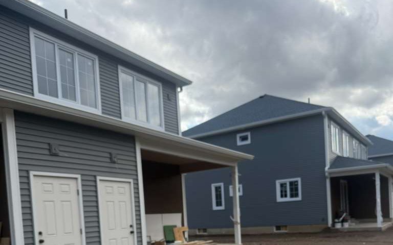 Two homes with freshly painted grey siding and white trim on a Prime Paint exterior job