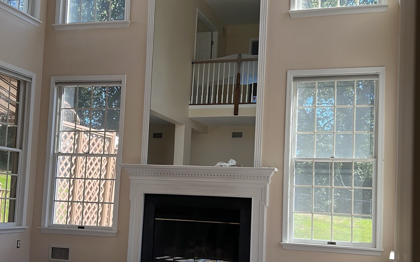 Two-story great room repainted by Prime Paint, fireplace and arched windows with the floor covered